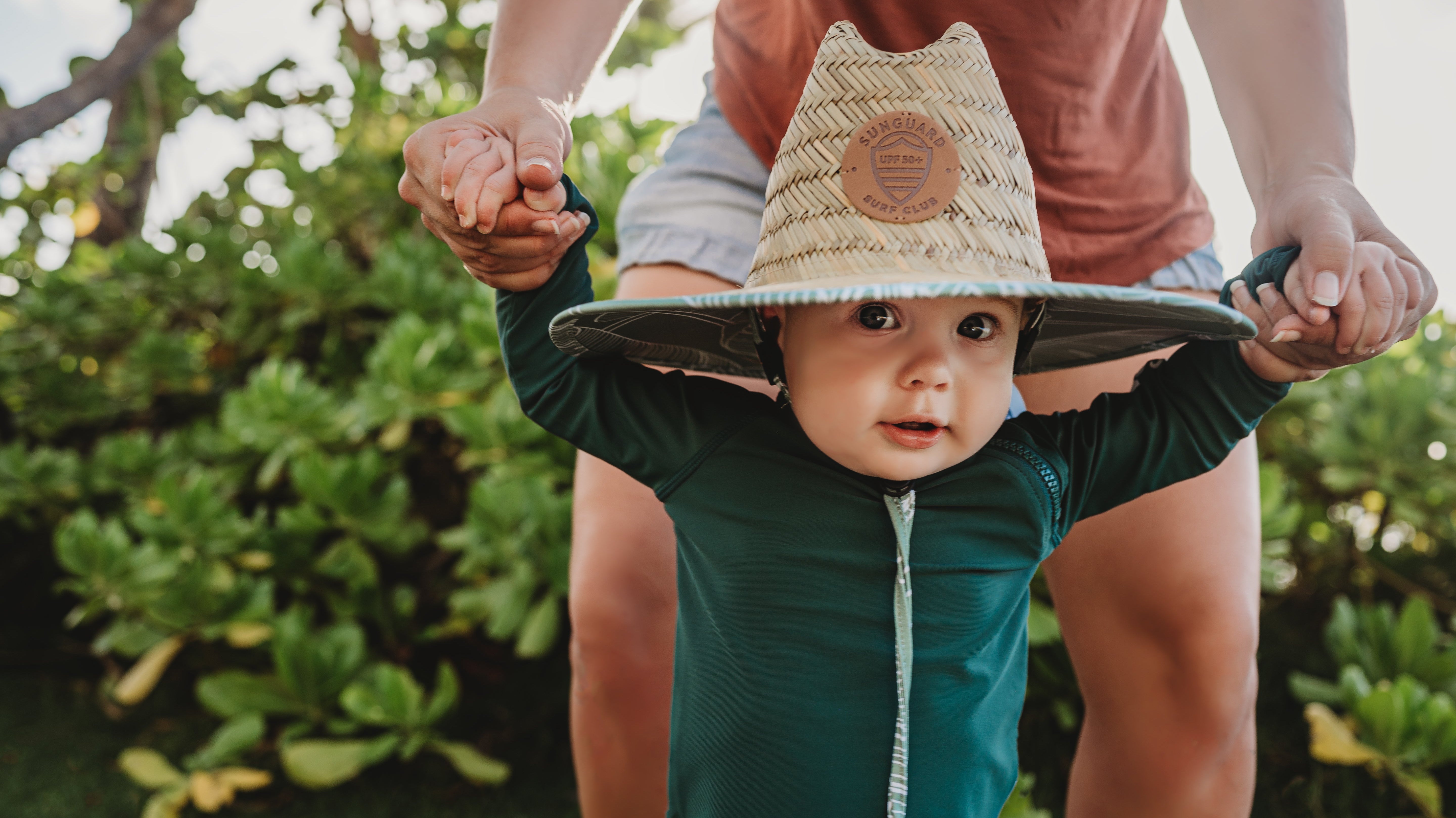 Baby wearing Sunguard Swim UPF 50+ straw lifeguard sun hat on the beach, providing full face and neck protection.