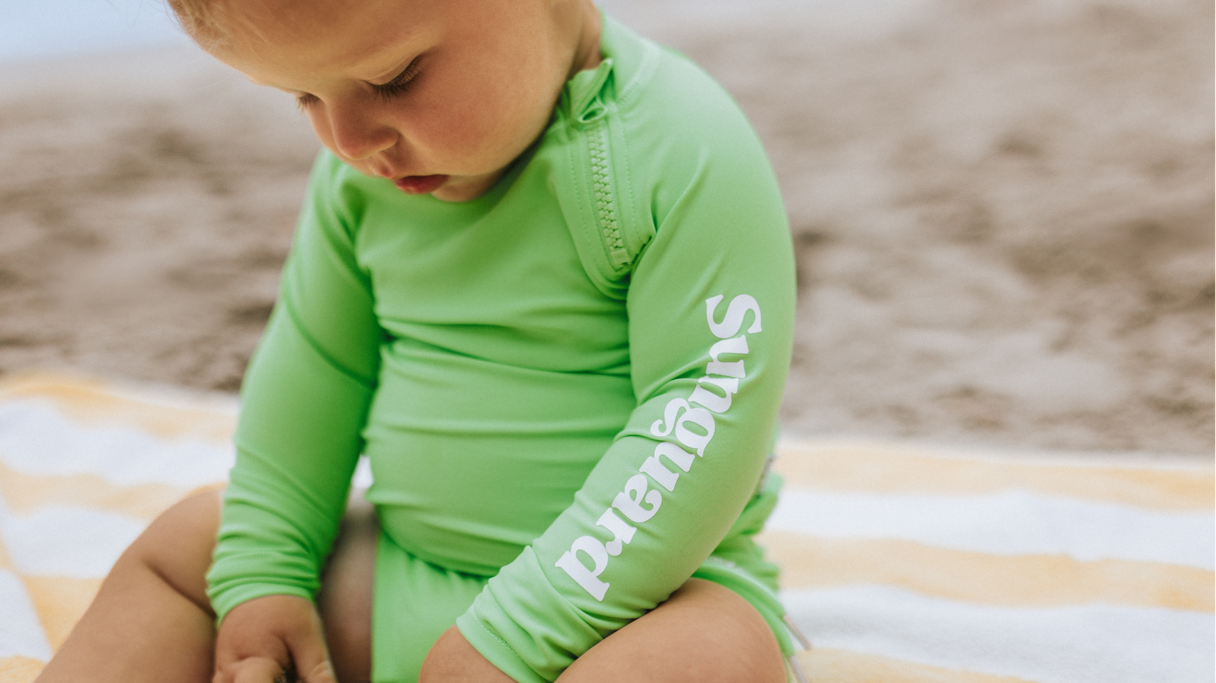 Baby boy wearing a UPF50+ rashguard swimming top