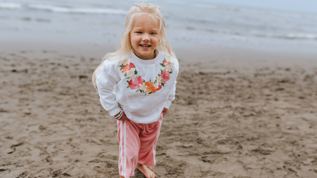 Little girl at the beach wearing a white sweater