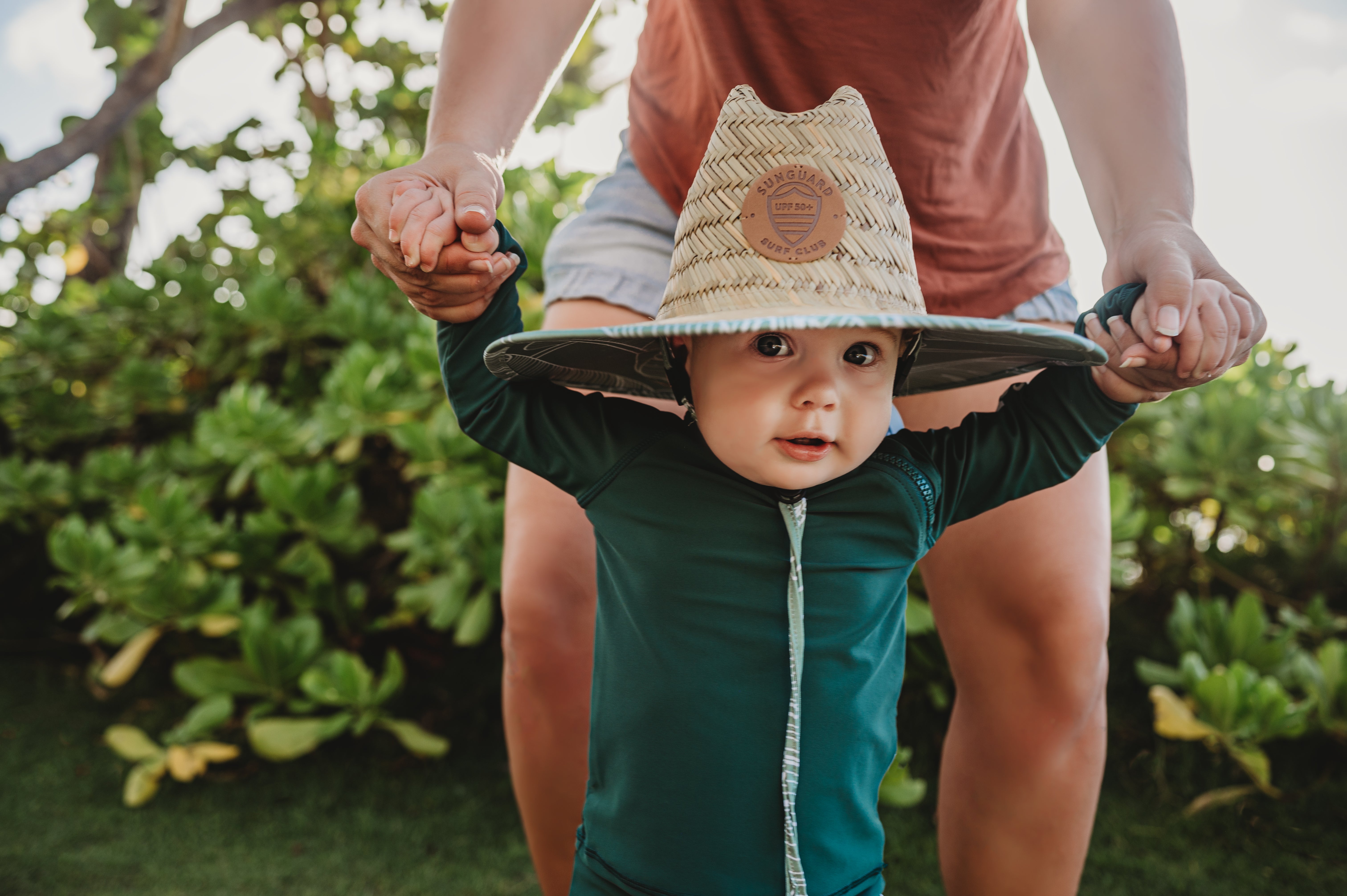 Baby wearing Sunguard Swim UPF 50+ straw lifeguard sun hat on the beach, providing full face and neck protection.