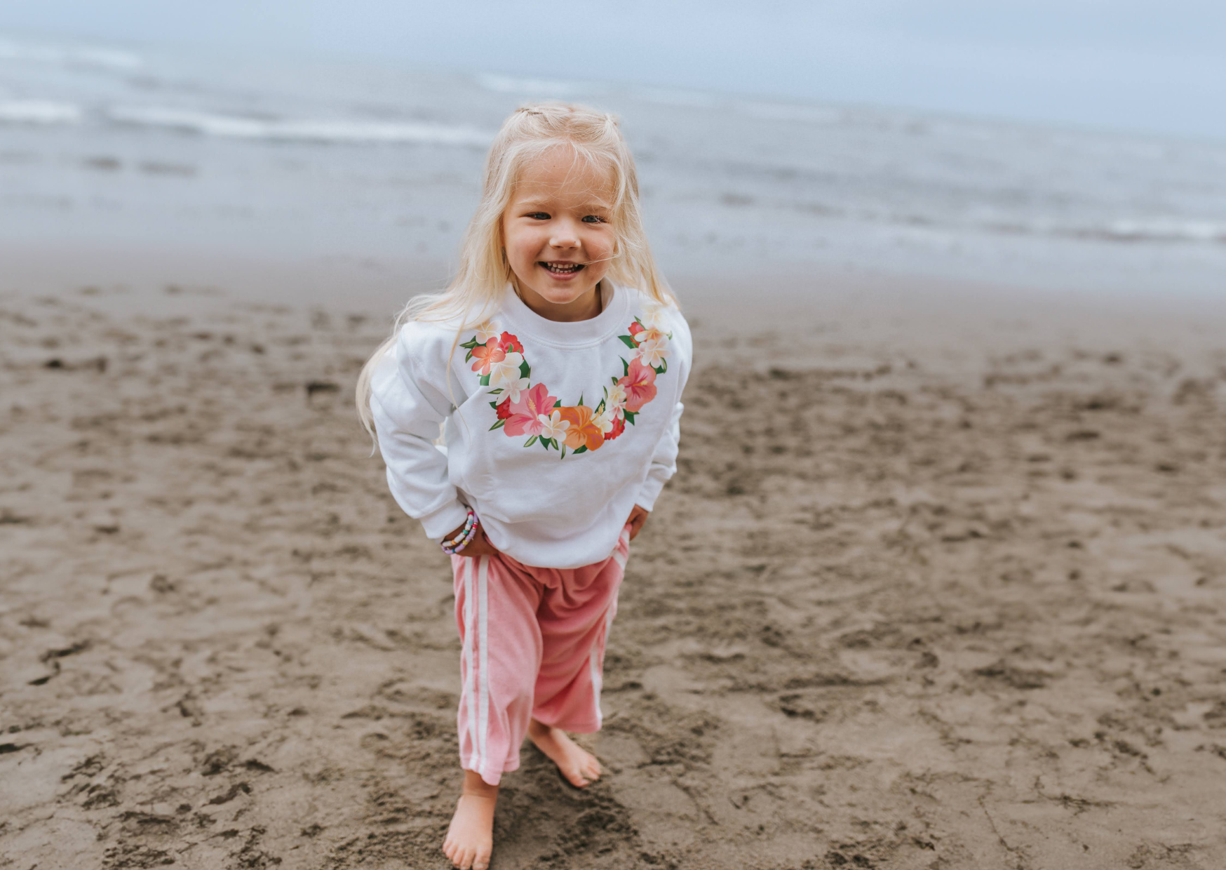 Little girl at the beach wearing a white sweater